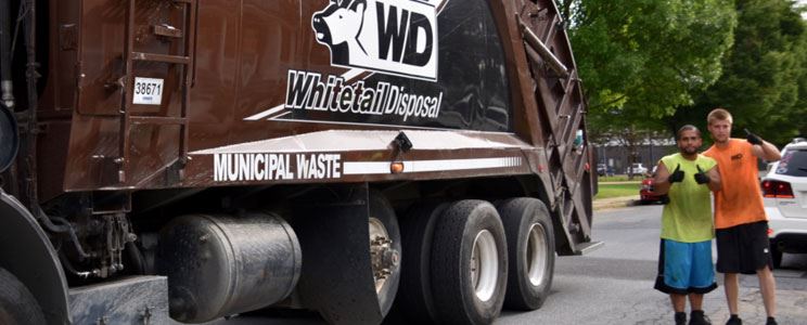 Two Men Giving Thumbs-Ups Beside a Whitetail Disposal Dump Truck